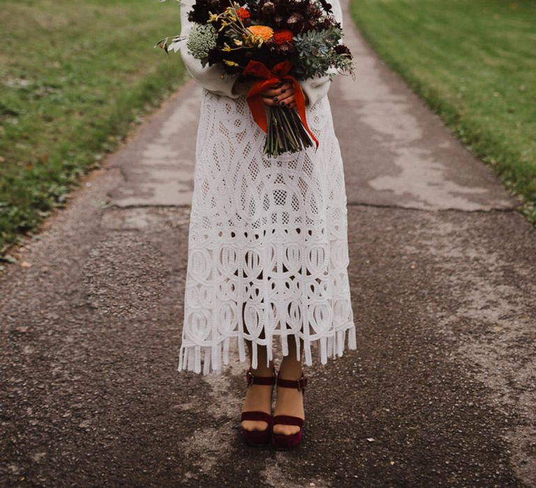 Bride in a crochet wedding dress and roll neck jumper for an outdoor woodland wedding ceremony 