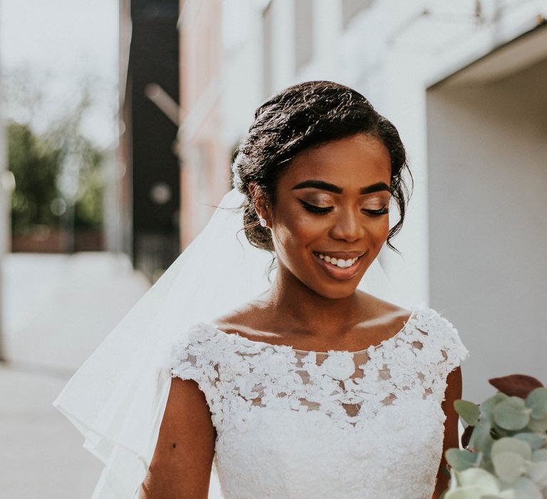 Beautiful black bride in a lace wedding dress with shimmering eyeshadow and winged eyeliner 