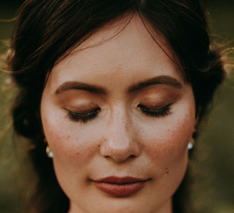 Beautiful bride with freckles wearing brown eyeshadow, pencil eyeliner and lash extensions wedding makeup 