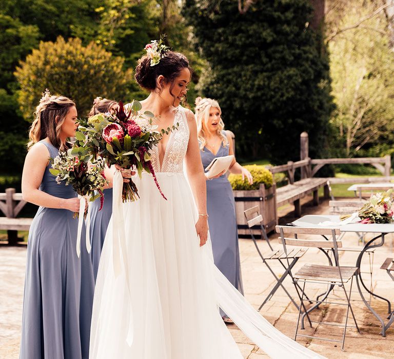 Bride with curly pinned undo wearing Riley dress Made With Love bridal clutching bouquet