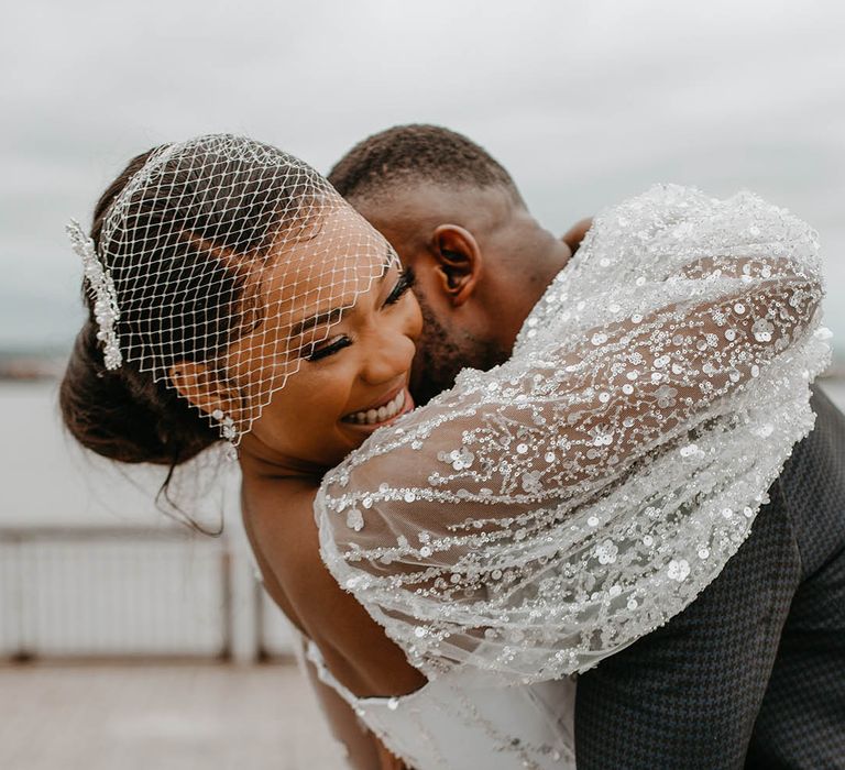 Groom hugs his bride closely and she wraps her arms around his neck on their wedding day