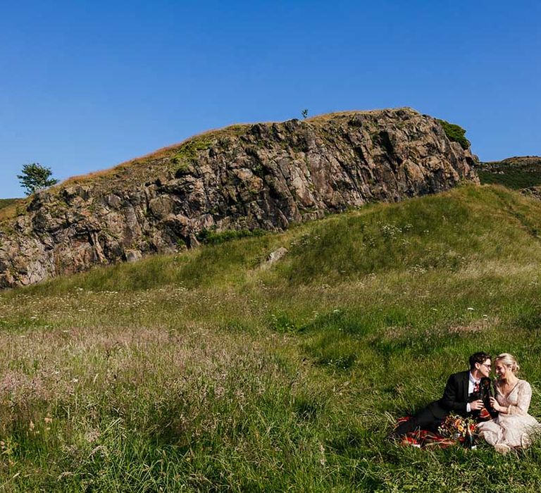 Bride & groom sit on hilltop in Scotland on their wedding day