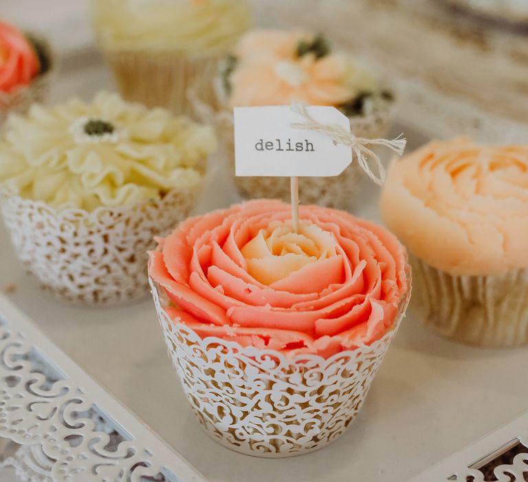 Mixed cupcakes with rose petal icing and rustic label reading 'delish' 