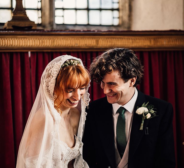 Bride and groom laugh as they sign the wedding register