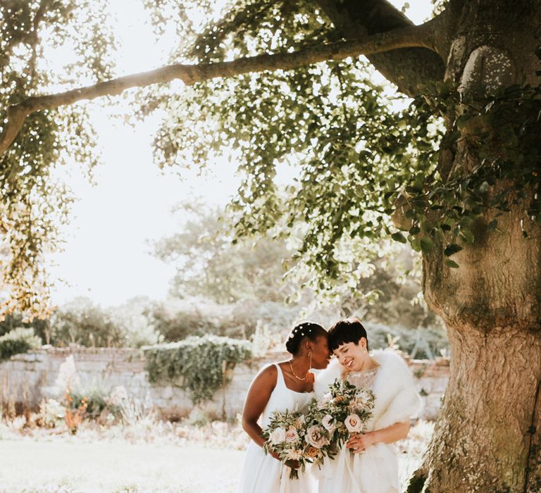 Romantic wedding photograph under a tree of two brides at their LGBTQI+ Elmore Court wedding 