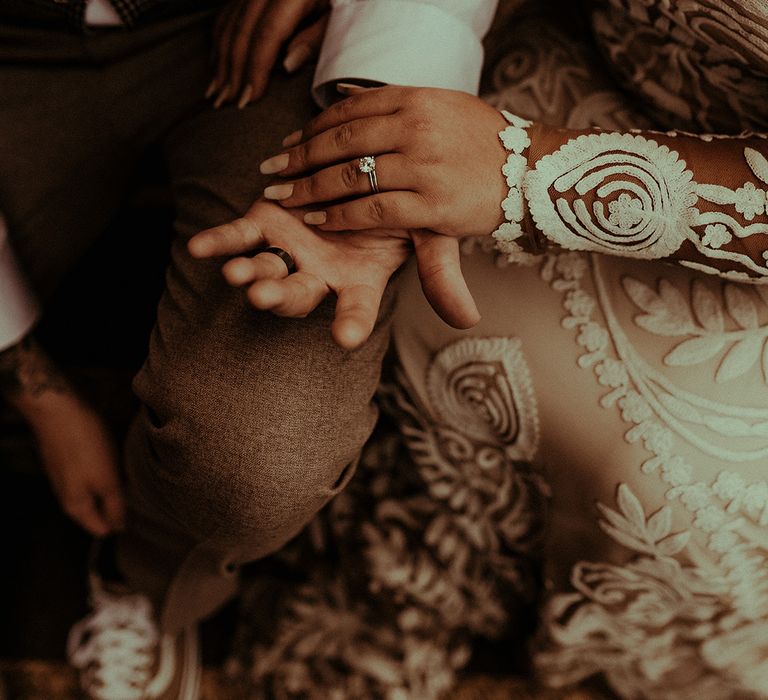 Bride in a lace long sleeve wedding dress showing off her solitaire diamond engagement ring and wedding band 