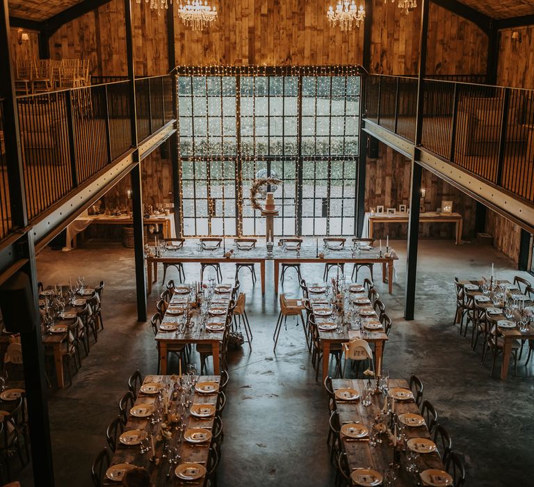 Interior of rustic barn wedding reception at Hidden River Barn with wooden wedding tables and fairy light curtain