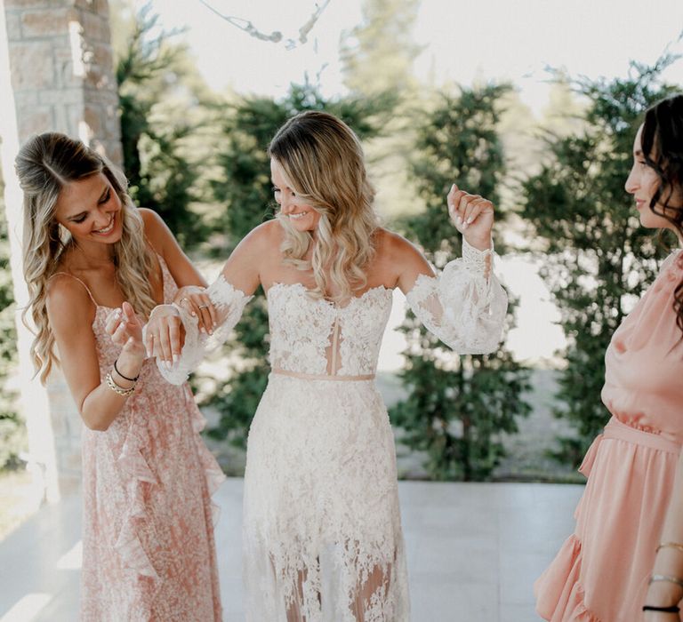 Bride stands with bridesmaids who wear blush pink dresses 