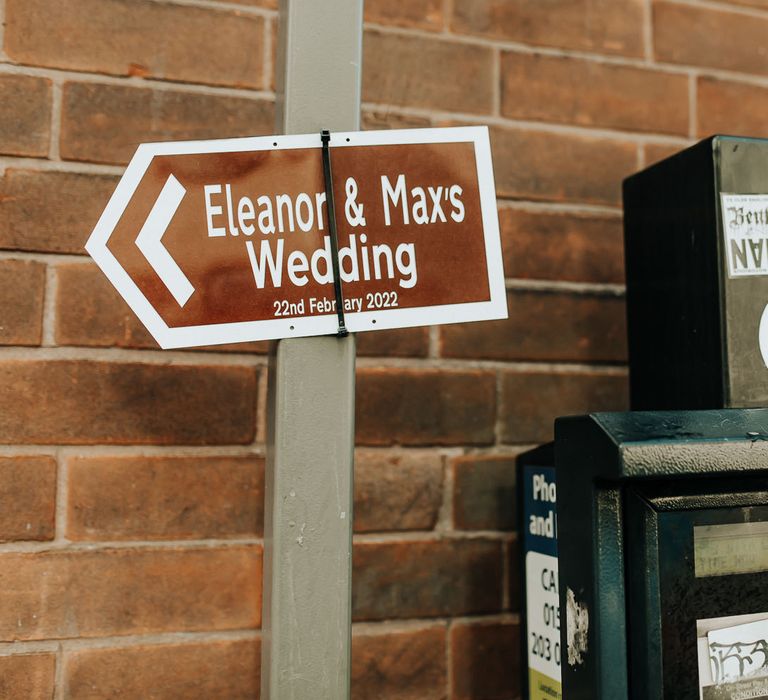 Brown wedding road sign reading 'Eleanor and Max's Wedding 22 February 2022'