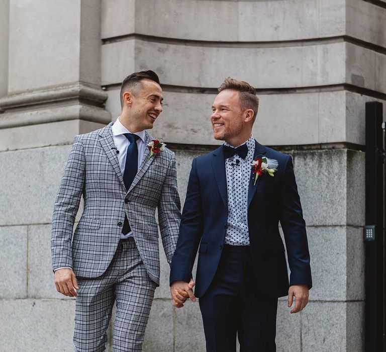 Grooms walk with one another on their wedding day outdoors 