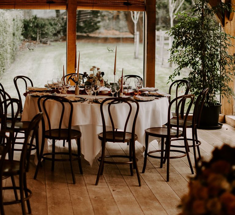 Round wedding tables with views of gardens and tapered orange candles