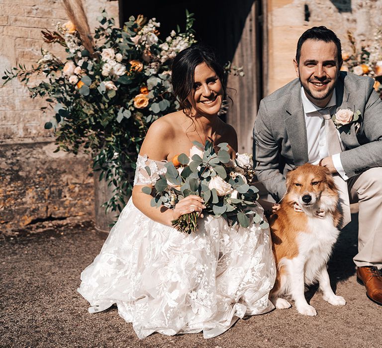 Bride and groom pose with their cute fluffy dog with love heart patterned bow tie