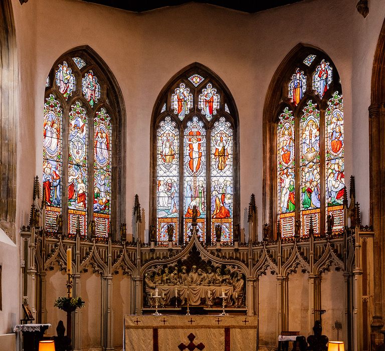 Grand church wedding venue with stained glass windows and elaborate gold religious paraphernalia  