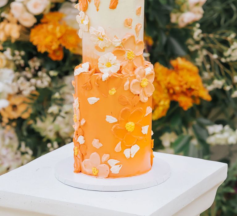 Tall two tier bright orange and white wedding cake with iced flowers 