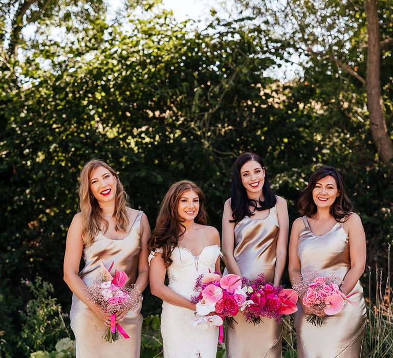 Bridesmaids wear satin champagne bridesmaid dresses and stand with bride who wears lace wedding dress 