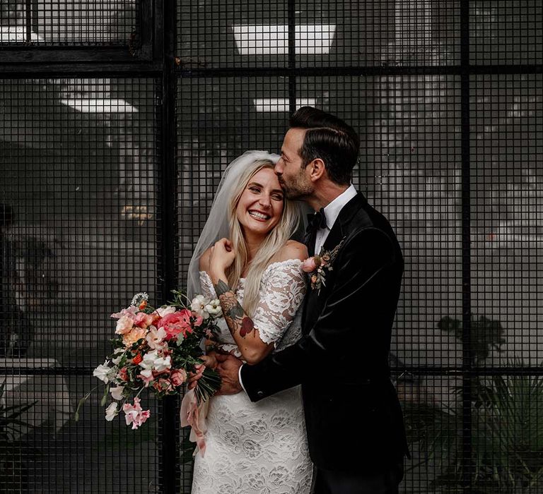 Bride in boho two piece lace bridal outfit with large mixed colourful bouquet and groom in dark tux with bowtie