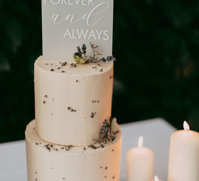 Lavender and white pillar candles with transparent engraved cake topper and two tier buttercream wedding cake with white rose and dried lavender decorations