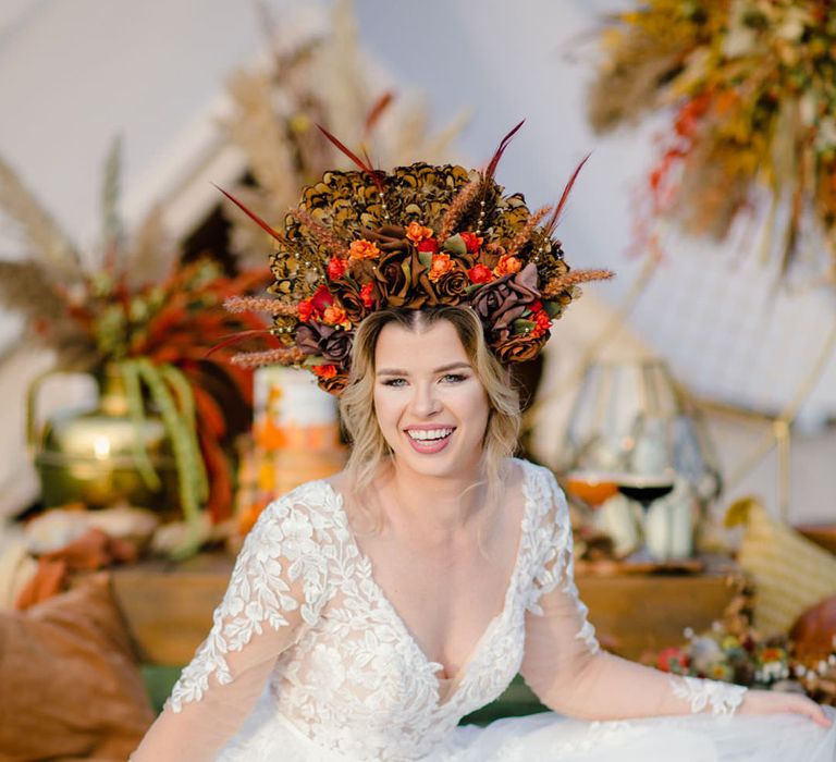 Bride in bold autumnal headpiece with brown & orange silk flowers and pheasant feather details and v neck lace detail wedding dress 