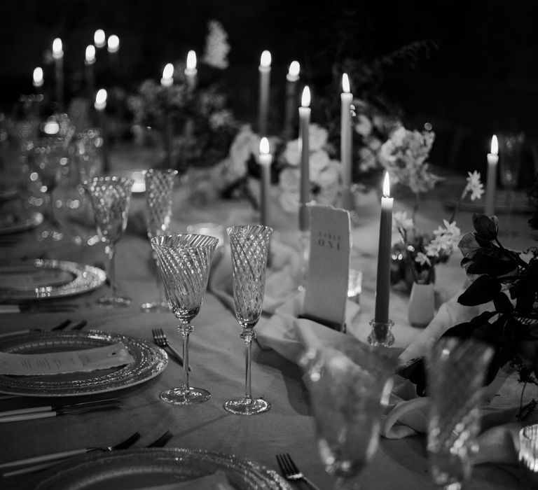 Black and white photo of minimalist wedding tablescape with white tablecloth, white table runner, tapered candles and minimalistic wedding stationery 