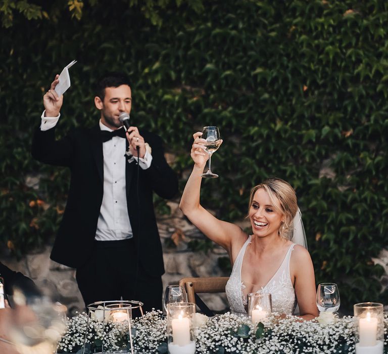 Groom in black-tie gives speech during outdoor reception 