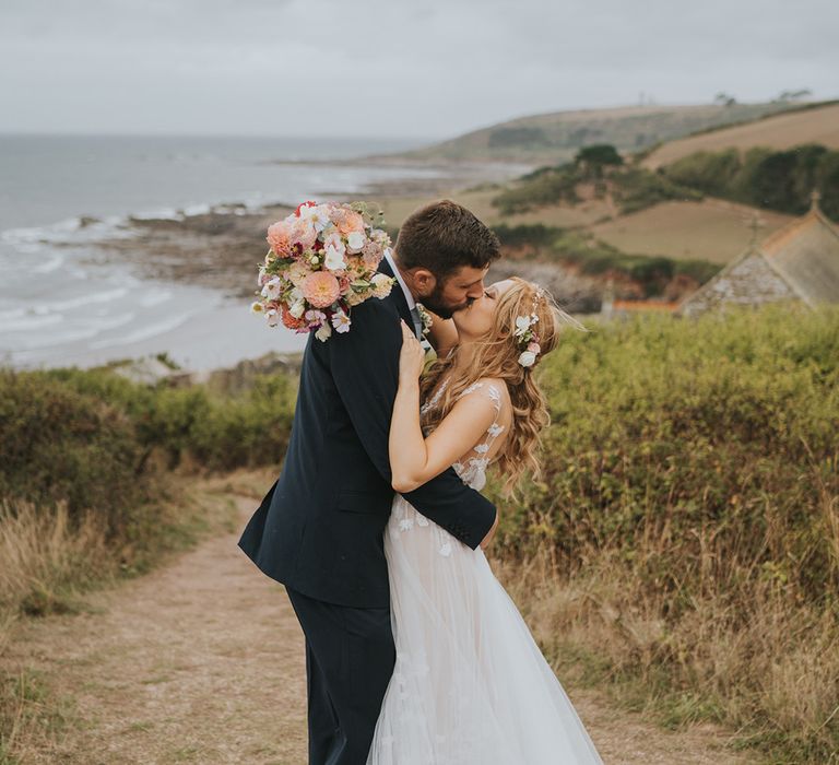 Bride in Anna Kara wedding dress kissing groom in navy wedding suit for special day 