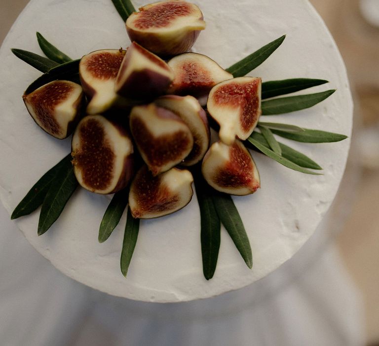 Simple white iced ewedding cake with fig and olive leaf decor