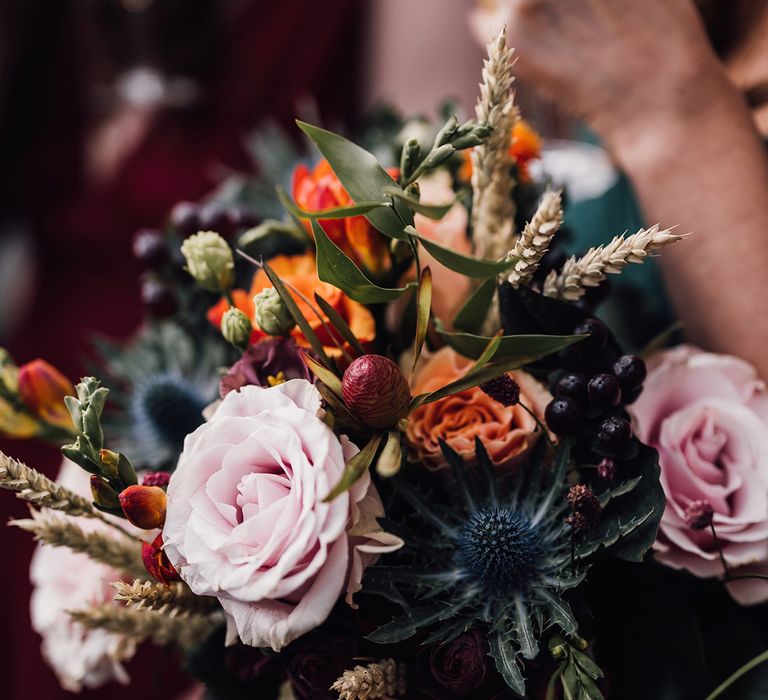 Pink and orange roses with thistles and winter berries for November wedding at Cripps Barn wedding venue 