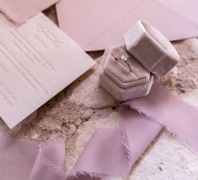 Velvet lilac wedding ring holder on stone floor with light purple and lilac wedding stationery 