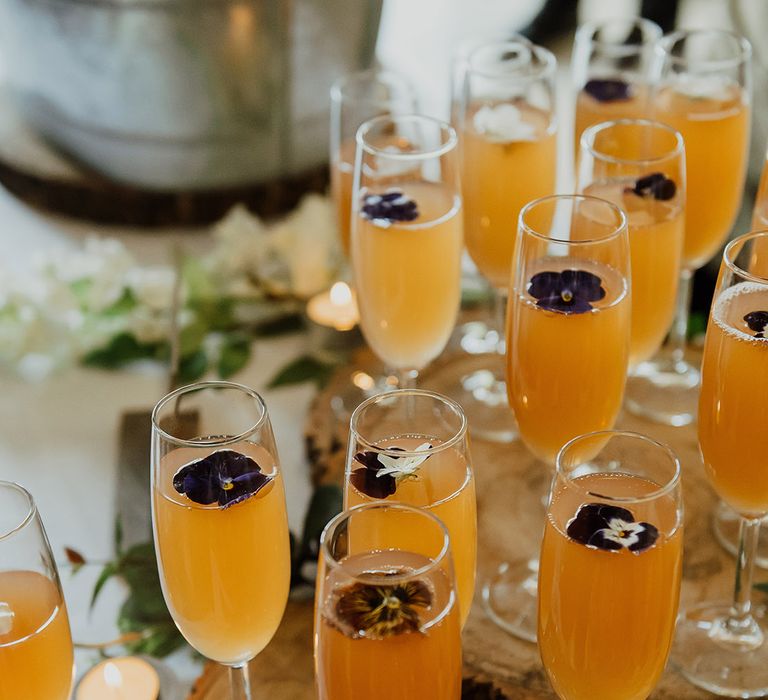 Glasses of mimosa with edible purple flowers for the wedding drinks