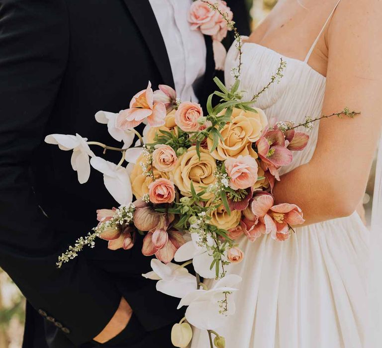 Bride holding blush toned bridal bouquet with poppies, ranunculus, roses, tulips and foliage at Euridge Manor wedding 