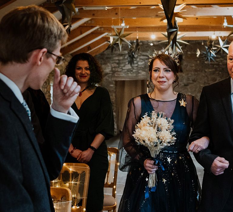 Father of the bride wearing a blue and white floral tie walks the bride to the end of the aisle to meet the groom 