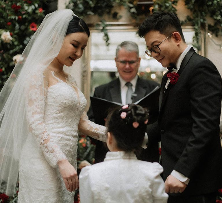 The bride and groom's daughter brings the weddings rings to the couple to complete the wedding ceremony 