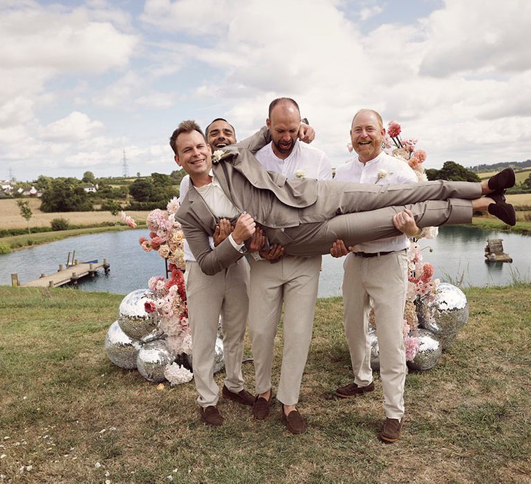 Anran wedding venue in Devon with groom in grey suit being held up by the groomsmen 