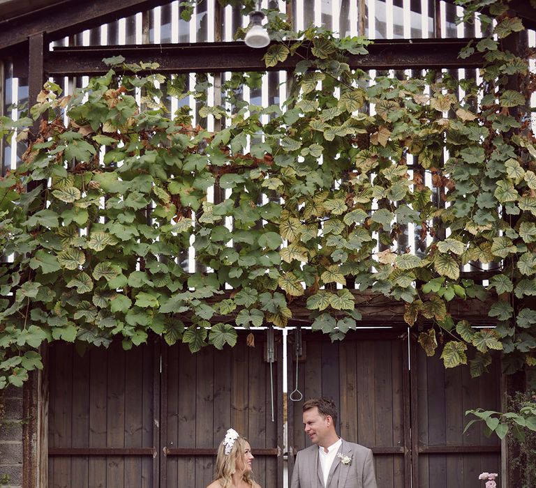 Bride in ruffle bridal gown and crown with the groom in a light grey suit for summer wedding 