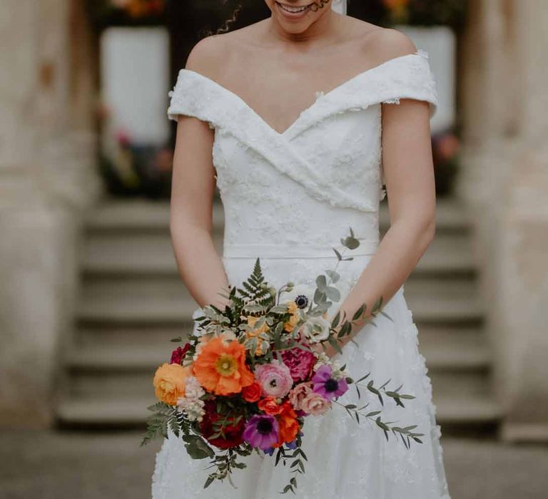 Bride in Suzanne Neville off shoulder 3D floral applique wedding dress holding spring-inspired bridal bouquet at Elmore Court Gloucestershire 