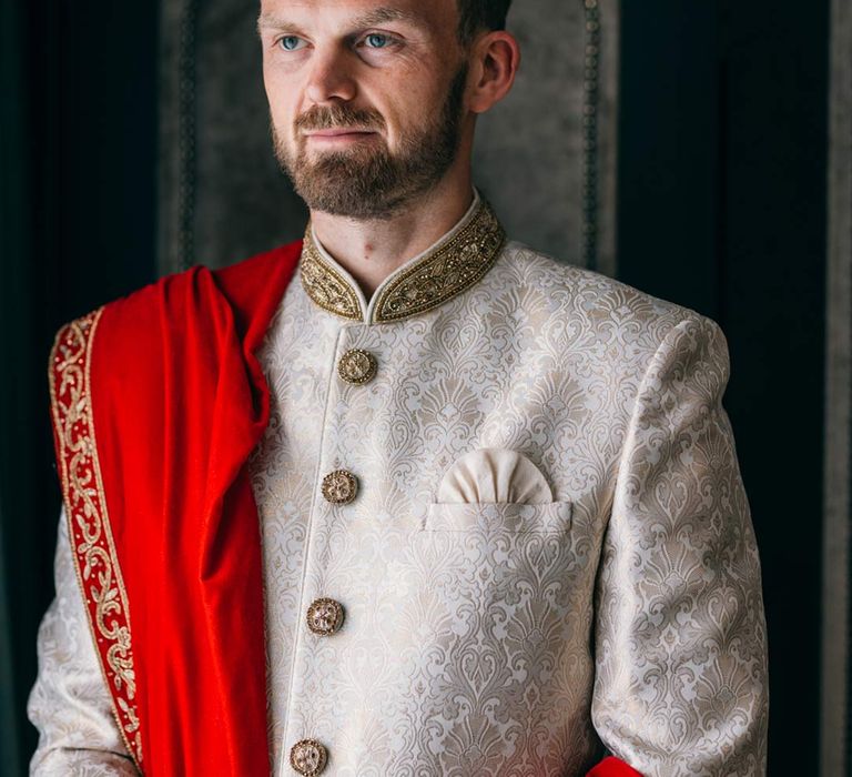 Groom wearing traditional white and gold sherwani 