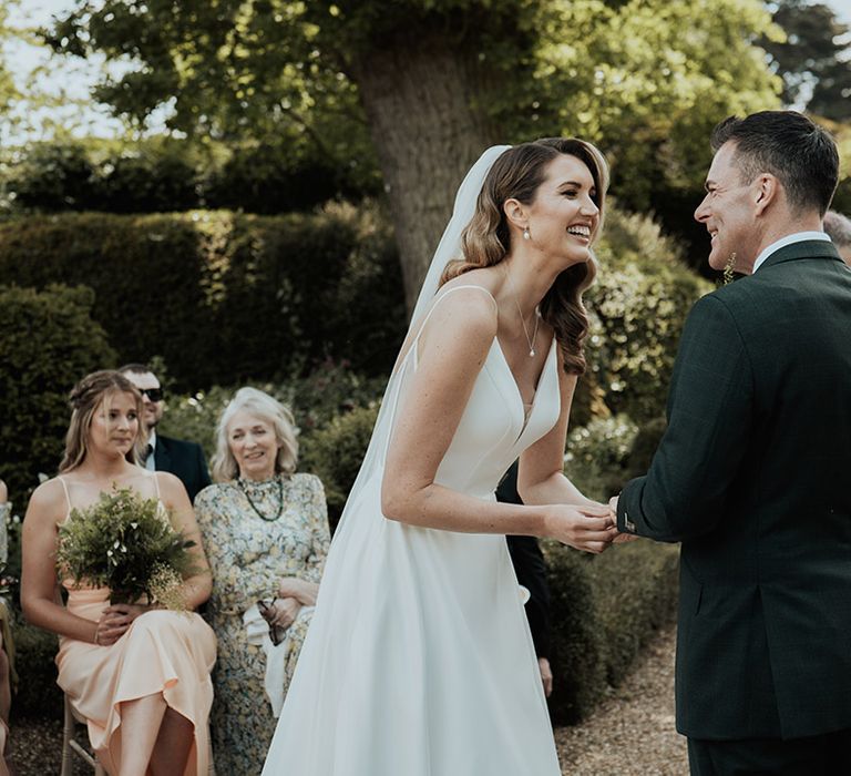 The bride and groom at their outdoor Kelmarsh Hall and Garden wedding surrounded by their guests 