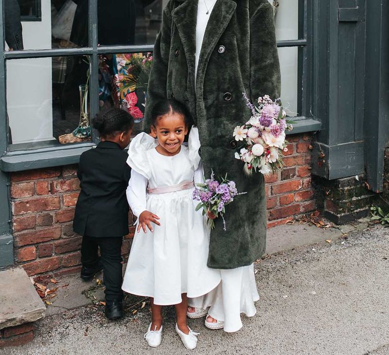 Bride in furry wedding coat with two of her younger children at the wedding 