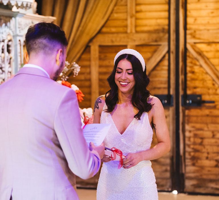 Bride wearing chunky pearl headband in a sparkly Made With Love wedding dress with groom in taupe suit 