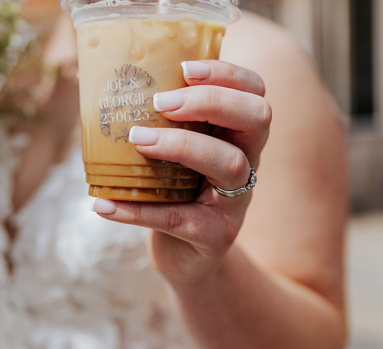 The bride holds an ice coffee from the coffee van with a personalised sticker 