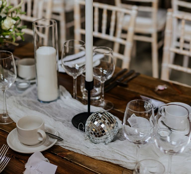 White table runner, white candles, silver disco balls, black candle holders and black cutlery make up the timeless wedding tablescape 