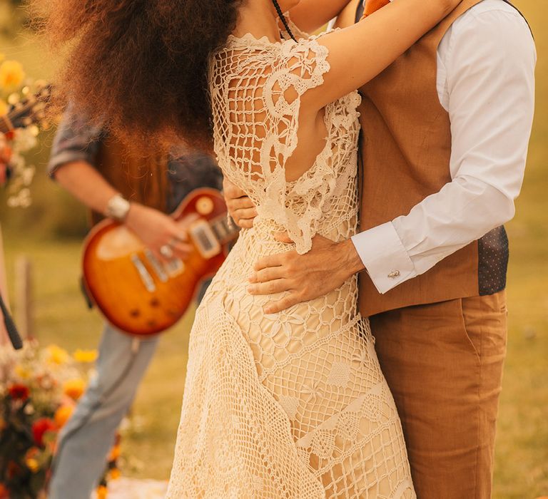 Bride in boho crochet gown for vintage Woodstock wedding inspiration with groom in brown linen suit 