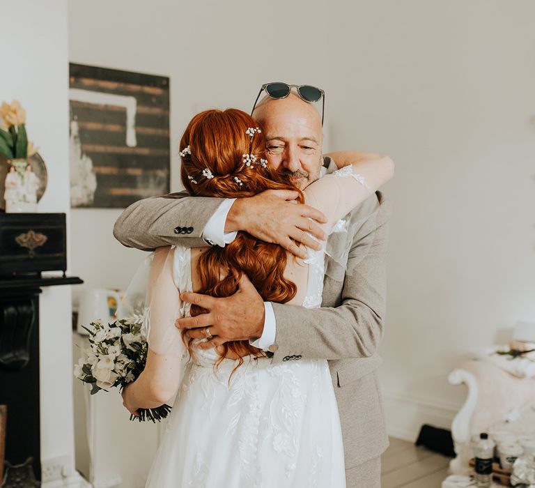 Father of the bride in light brown suit embraces the bride in emotional first look moment 