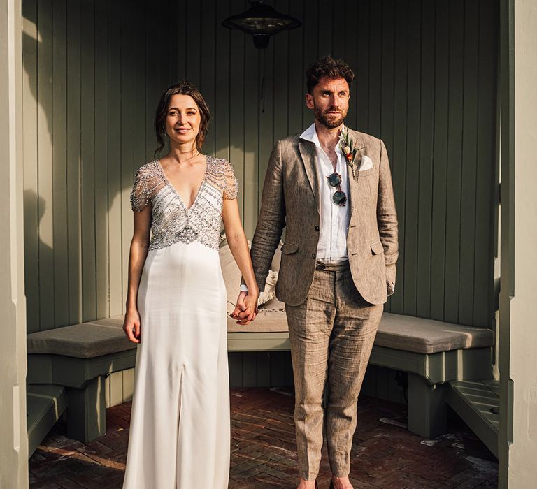 Bride in jewelled beaded Jenny Packham wedding dress with groom in grey suit 