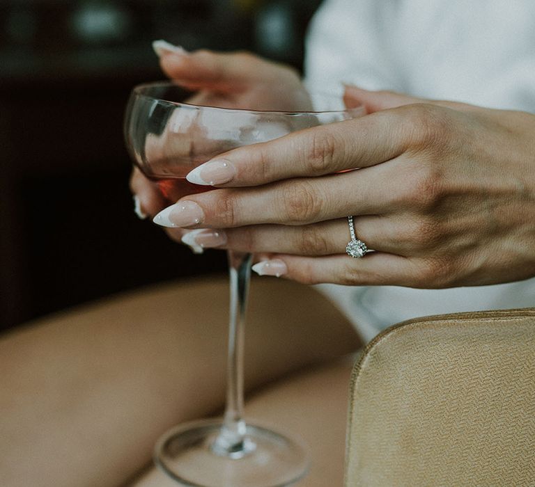 Bride with pearl wedding nails and small round engagement ring with halo 