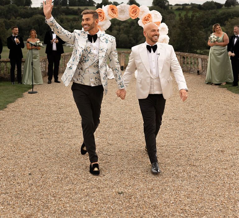 Two grooms celebrating was they walk back down the aisle as a married couple 