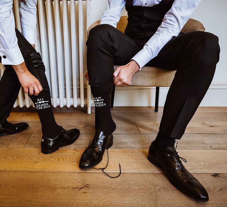 The two grooms wear personalised black wedding socks as keepsakes for their wedding day 