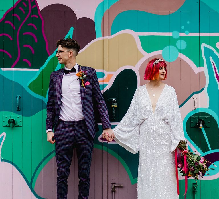 Bride in bat wing sequin wedding dress with groom in purple and black checkered wedding suit 