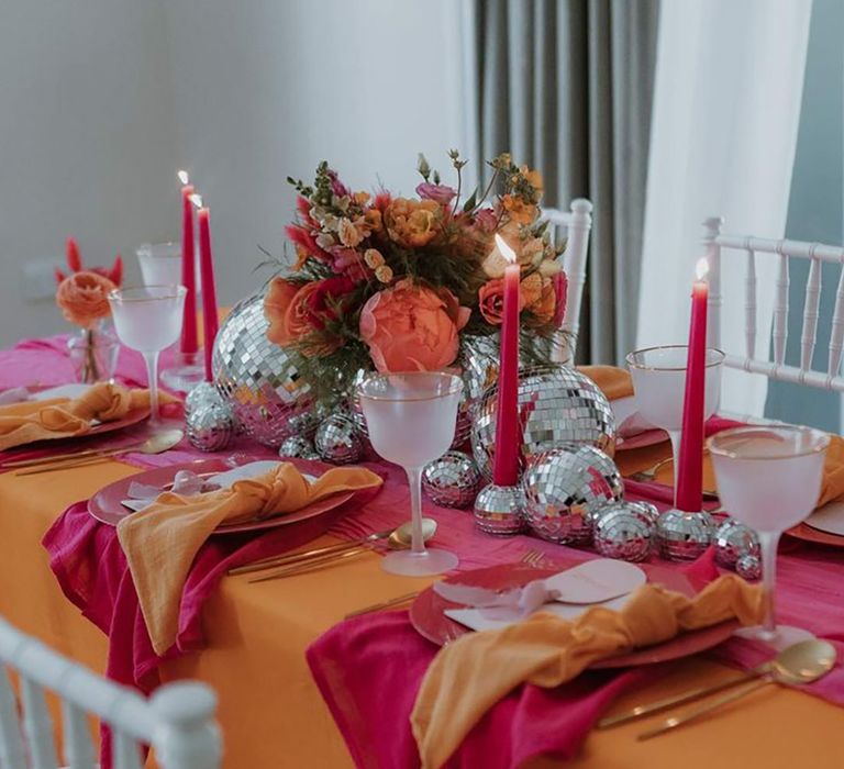 Pink and orange wedding theme tablescape with colourful candles and disco balls 