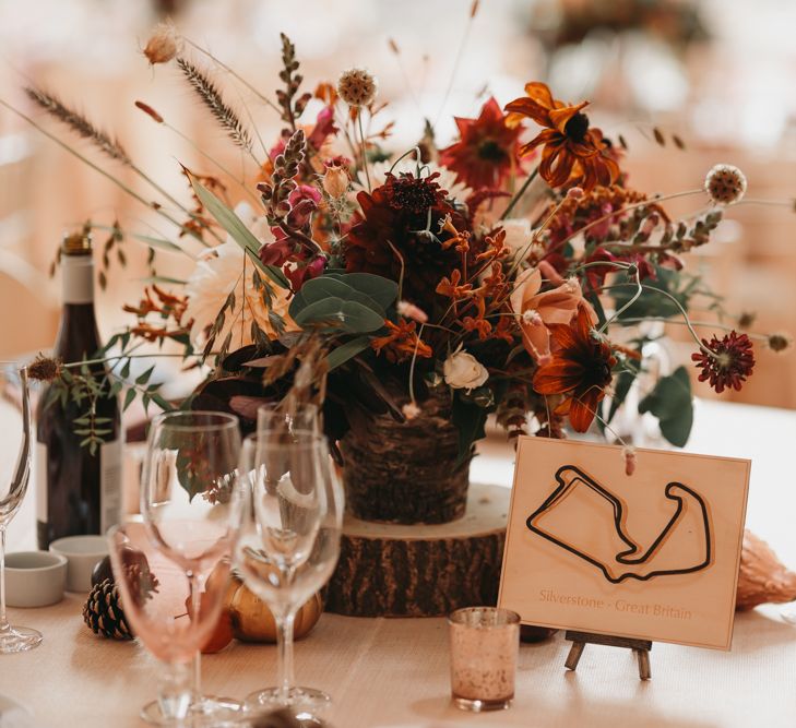 Rustic centrepiece with wooden tree slice and grand prix track table names and signs 